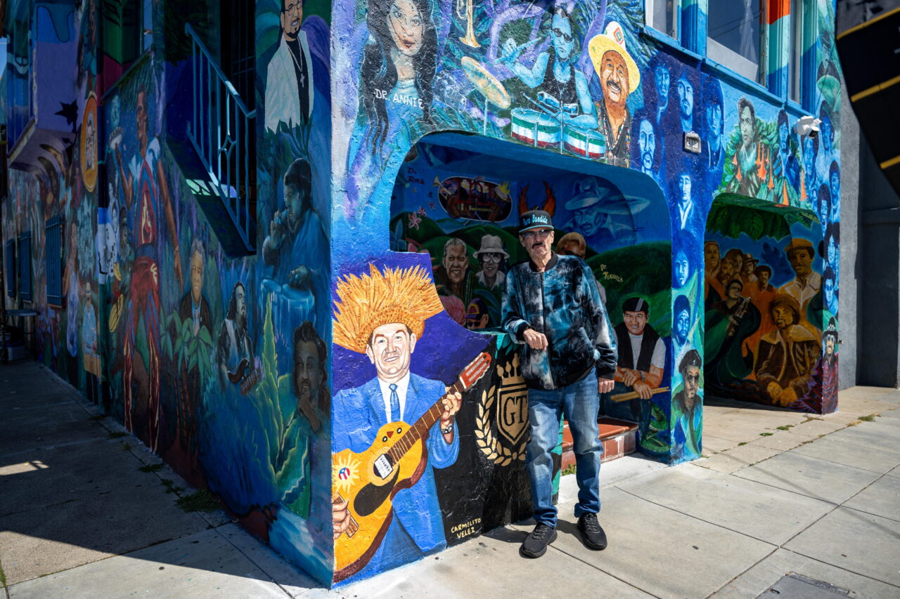 Richard Segovia stands in front of his house on 25th and York streets, known as the Latin Rock House, in San Francisco on April 7, 2026. The home is covered in a large mural honoring dozens of musicians tied to the Mission District’s Latin rock scene, which Segovia has helped preserve for decades.