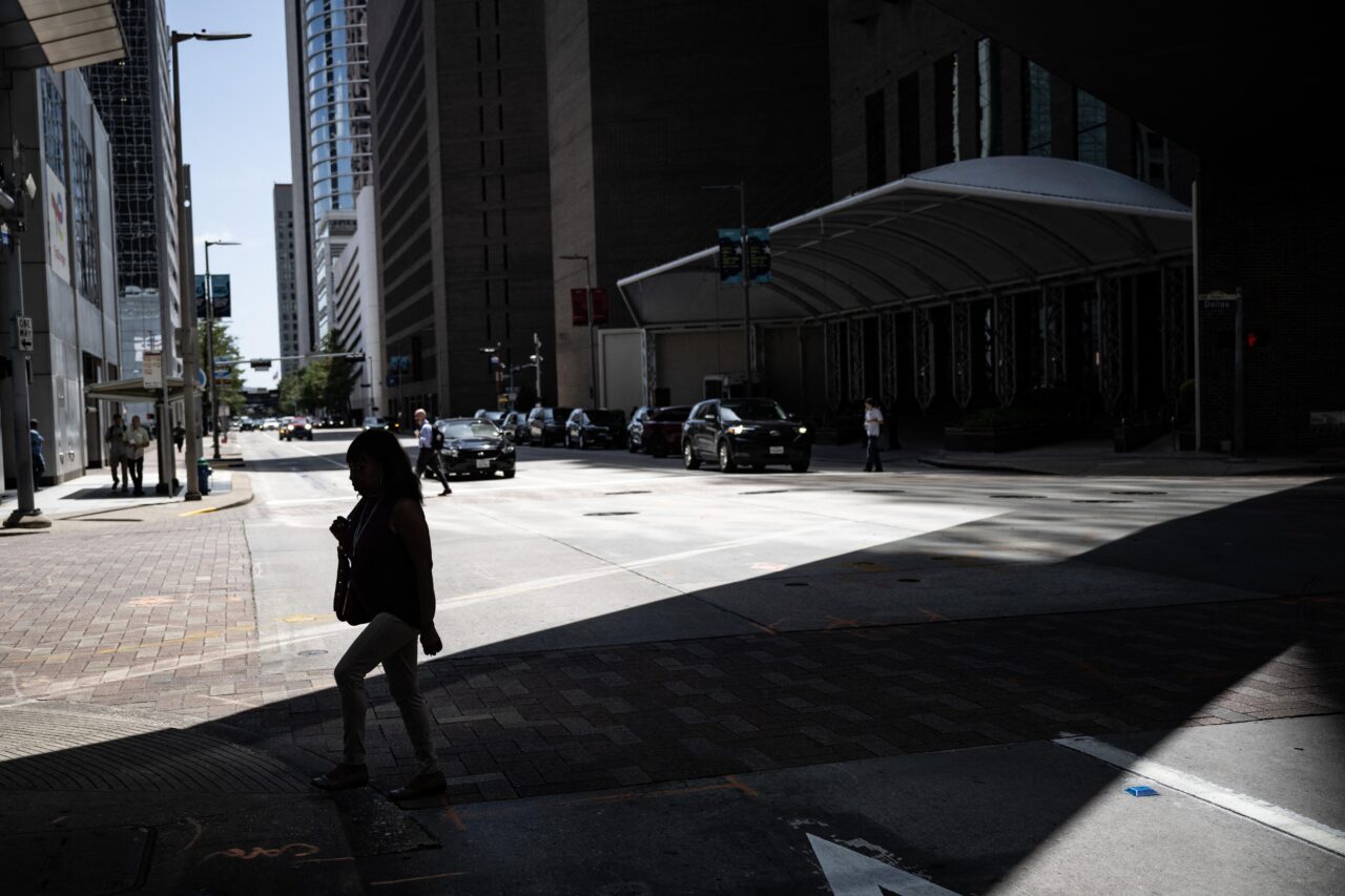 A woman walks in the shade in downtown Houston, Texas in late July 30 during a regional heat wave.