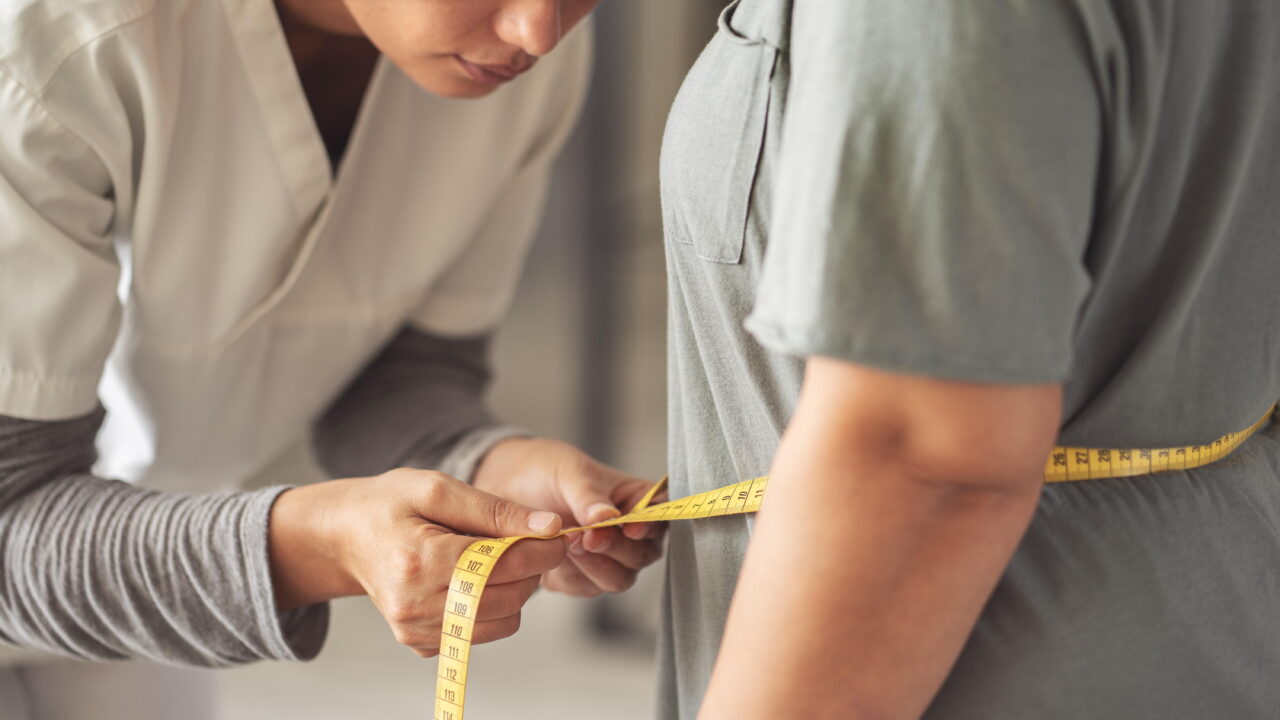 A healthcare professional measure's a patient's waist circumference.