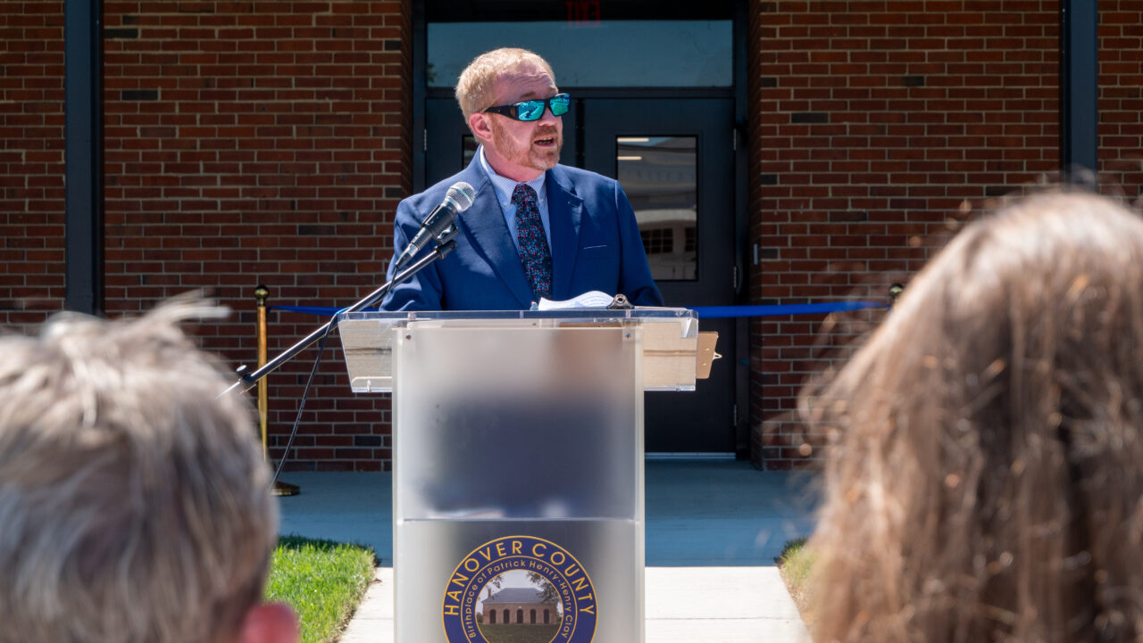 A man wearing reflective sunglasses is seen speaking at a podium in Hanover County, Virginia.