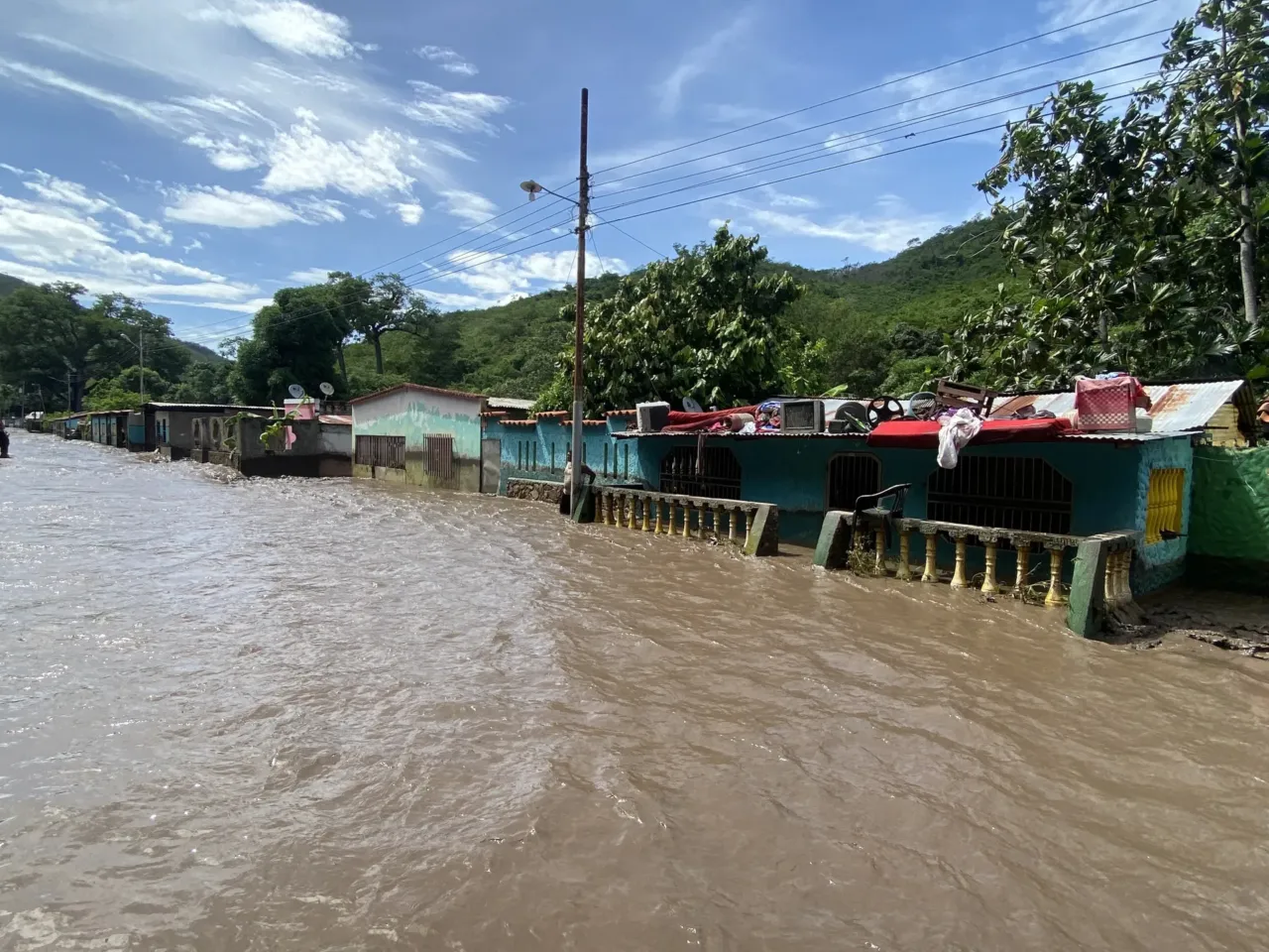 People stand outside their flooded homes after a river swelled due to heavy rains following the passage of Hurricane Beryl on the road from Cumana to Cumanacoa, Sucre State, Venezuela, on July 2, 2024. Hurricane Beryl churned towards Jamaica Tuesday after killing at least five people and causing widespread destruction across the southeastern Caribbean, threatening deadly winds and storm surge as it approached.