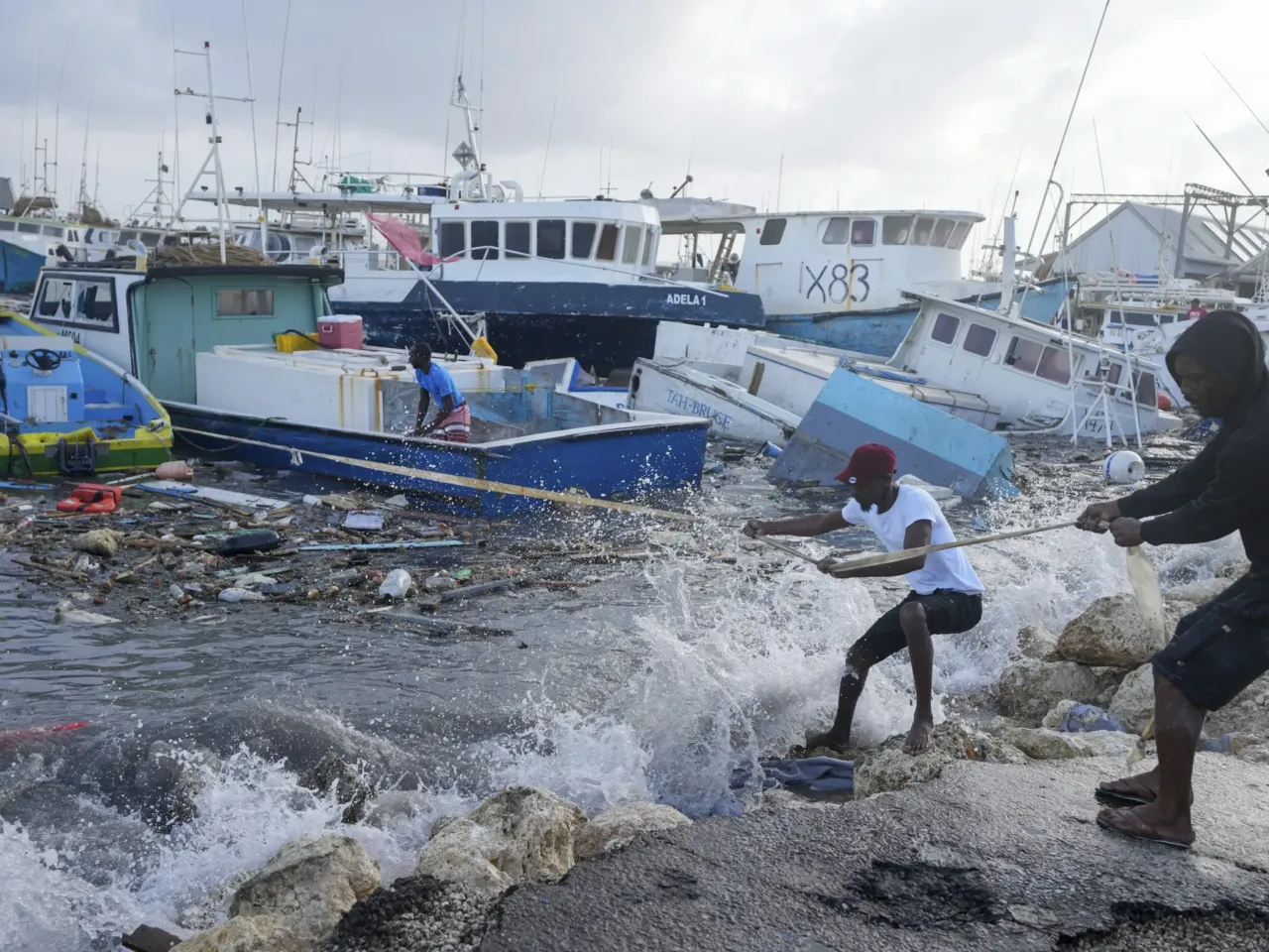 Fishermen pull a boat damaged by Hurricane Beryl back to the dock at the Bridgetown Fisheries in Barbados, Monday, July 1, 2024.
