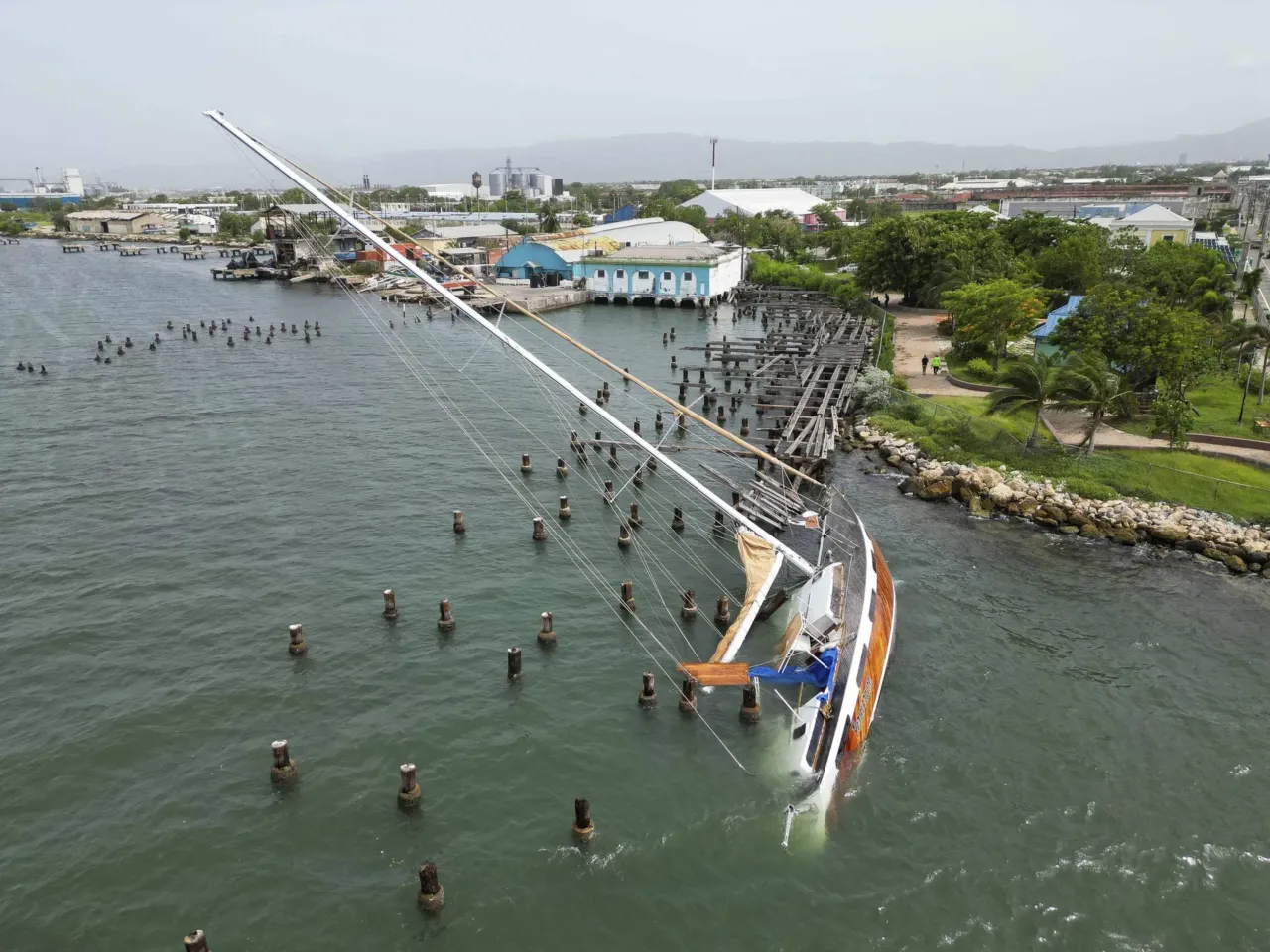 A boat damaged by Hurricane Beryl lays on its side at a dock in Kingston, Jamaica, Thursday, July 4, 2024.