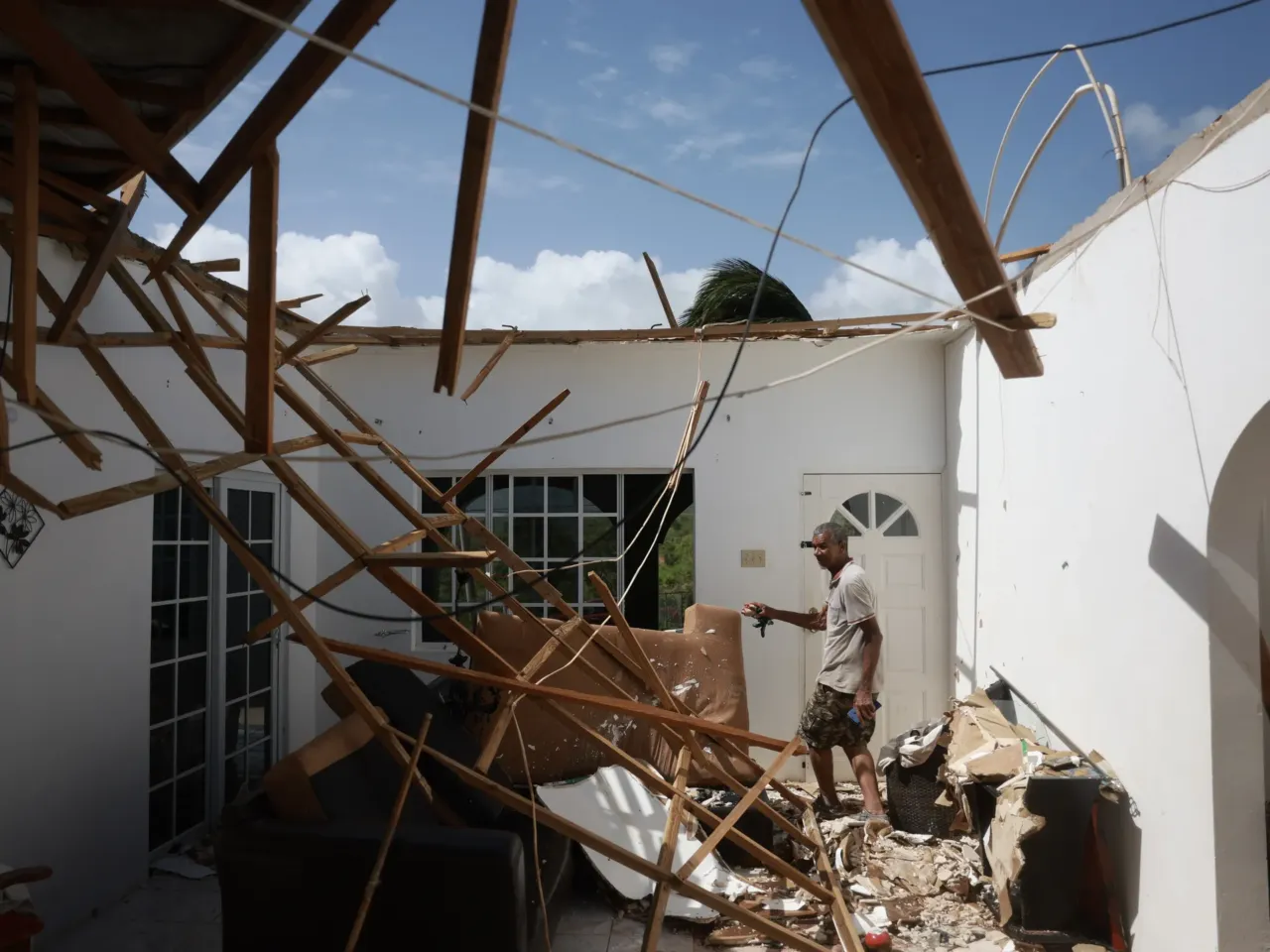Everton Evanks walks through his living room after the roof of the home was blown off by the winds from Hurricane Beryl as it passed through the area on July 4, 2024 in Saint Elizabeth Parish, Jamaica. Hurricane Beryl continues toward Mexico after passing through Caribbean islands, including Jamaica.