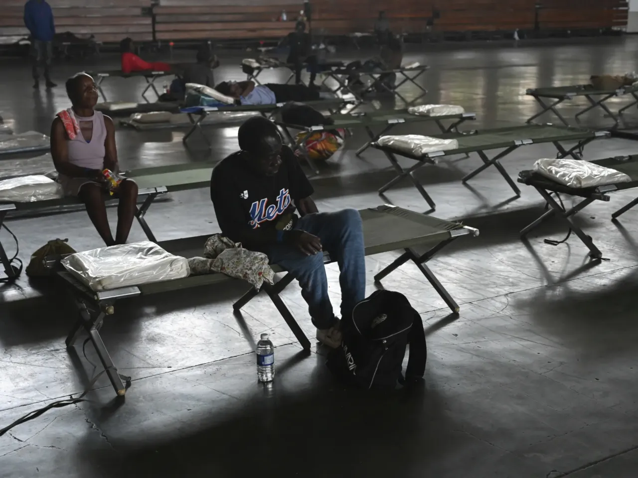 People sit on cots in the National Arena that has been transformed into a shelter in the aftermath of Hurricane Beryl, in Kingston, Jamaica, Thursday, July 4, 2024. Beryl ripped off roofs in Jamaica, jumbled fishing boats in Barbados and damaged or destroyed 95% of homes on a pair of islands in St. Vincent and the Grenadines before rumbling past the Cayman Islands early Thursday and taking aim at Mexico’s Caribbean coast.