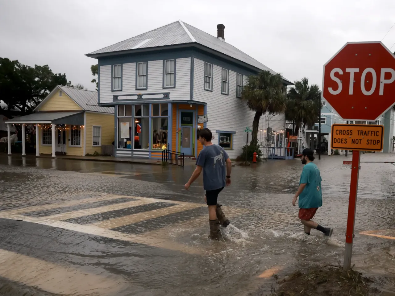People walk through a flooded street caused by the rain and storm surge from Hurricane Debby in Cedar Key, Florida, on Monday, August 5.