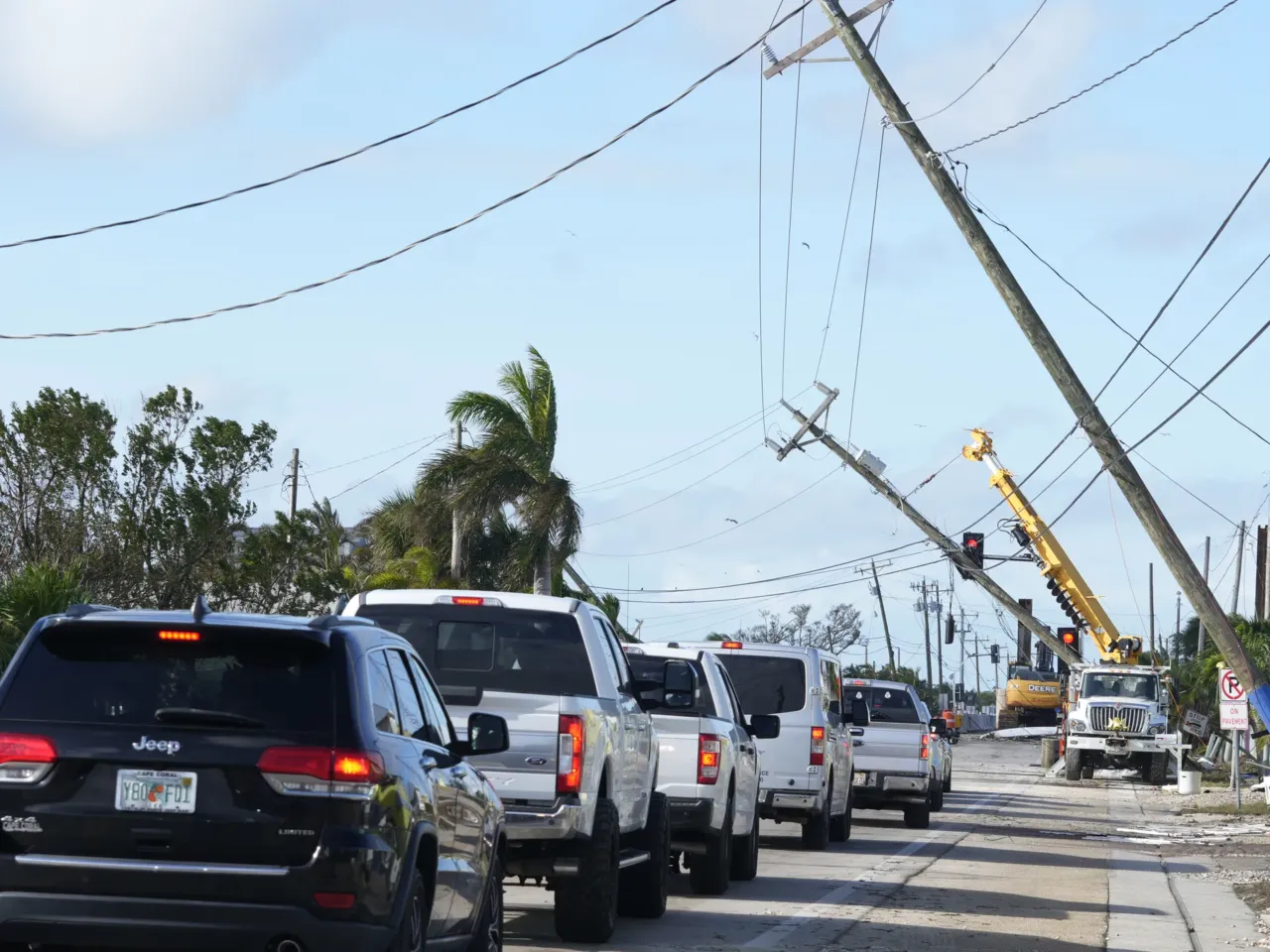 Cars move slowly after Hurricane Milton damaged power lines, in Matlacha, Fla.