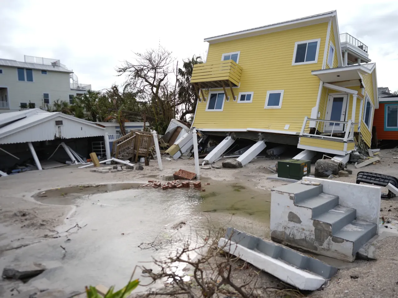 A house, center, lies toppled off its stilts after the passage of Hurricane Milton, alongside an empty lot where a home was swept away by Hurricane Helen, in Bradenton Beach on Anna Maria Island, Fla., on Thursday.