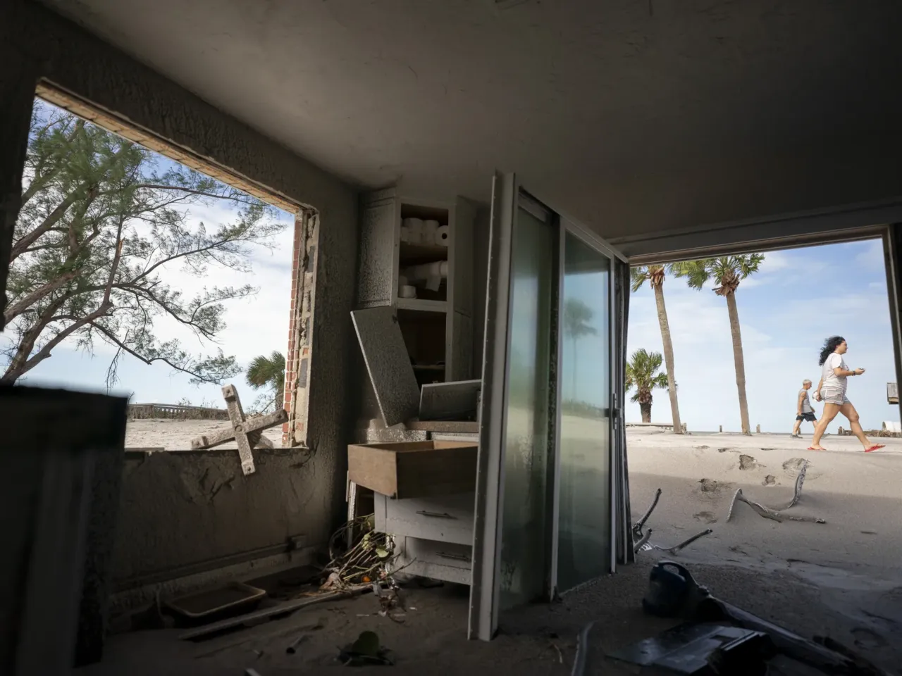 People walk near storm damaged beachside property in Venice, Florida on Thursday.