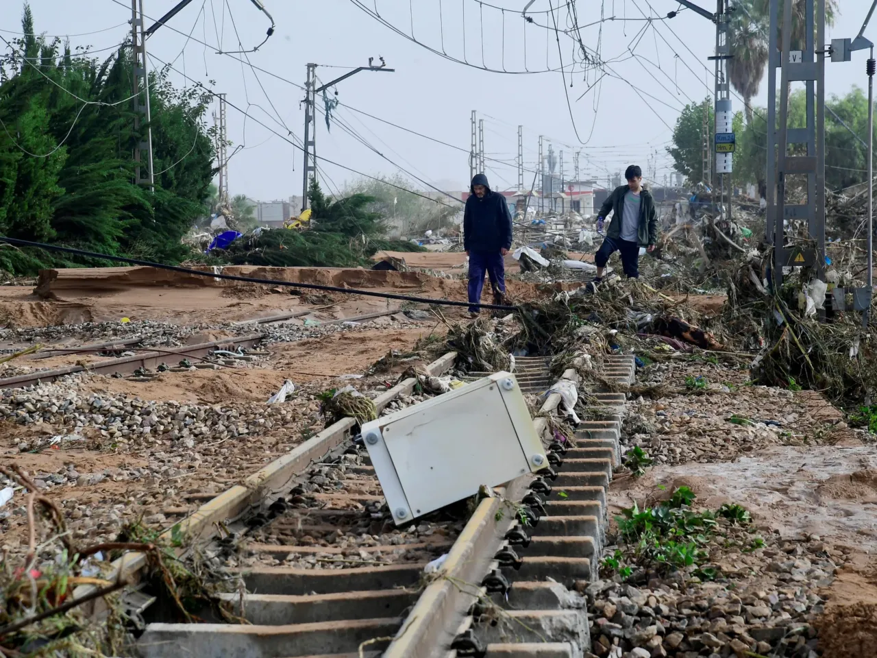 Residents walk among debris on a rail track following flood in Picanya, near Valencia, eastern Spain.