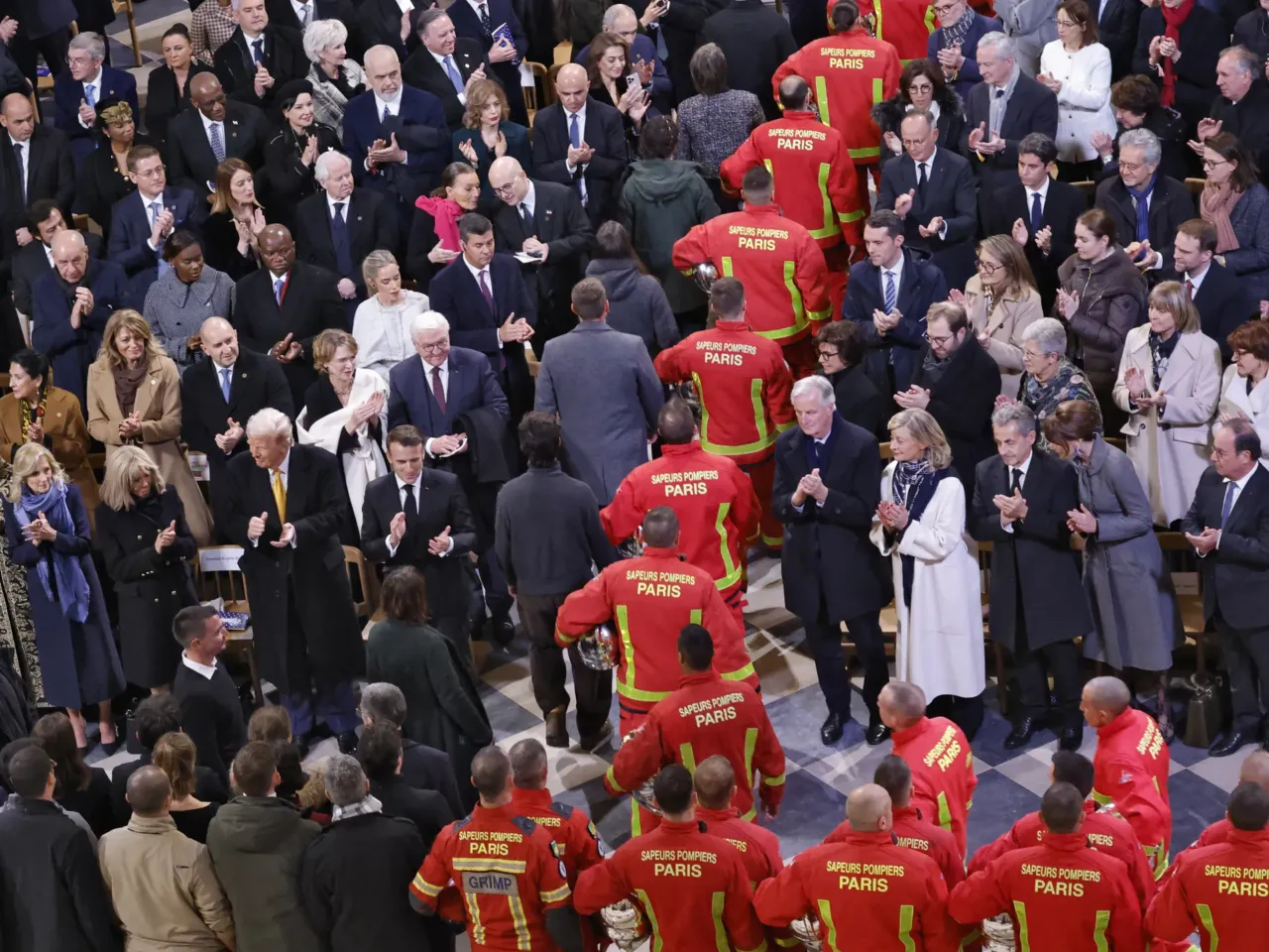 Firefighters, rescuers and builders involved in the restoration of Notre Dame Cathedral parade during a ceremony to mark the reopening of the landmark cathedral, in central Paris, on Saturday.