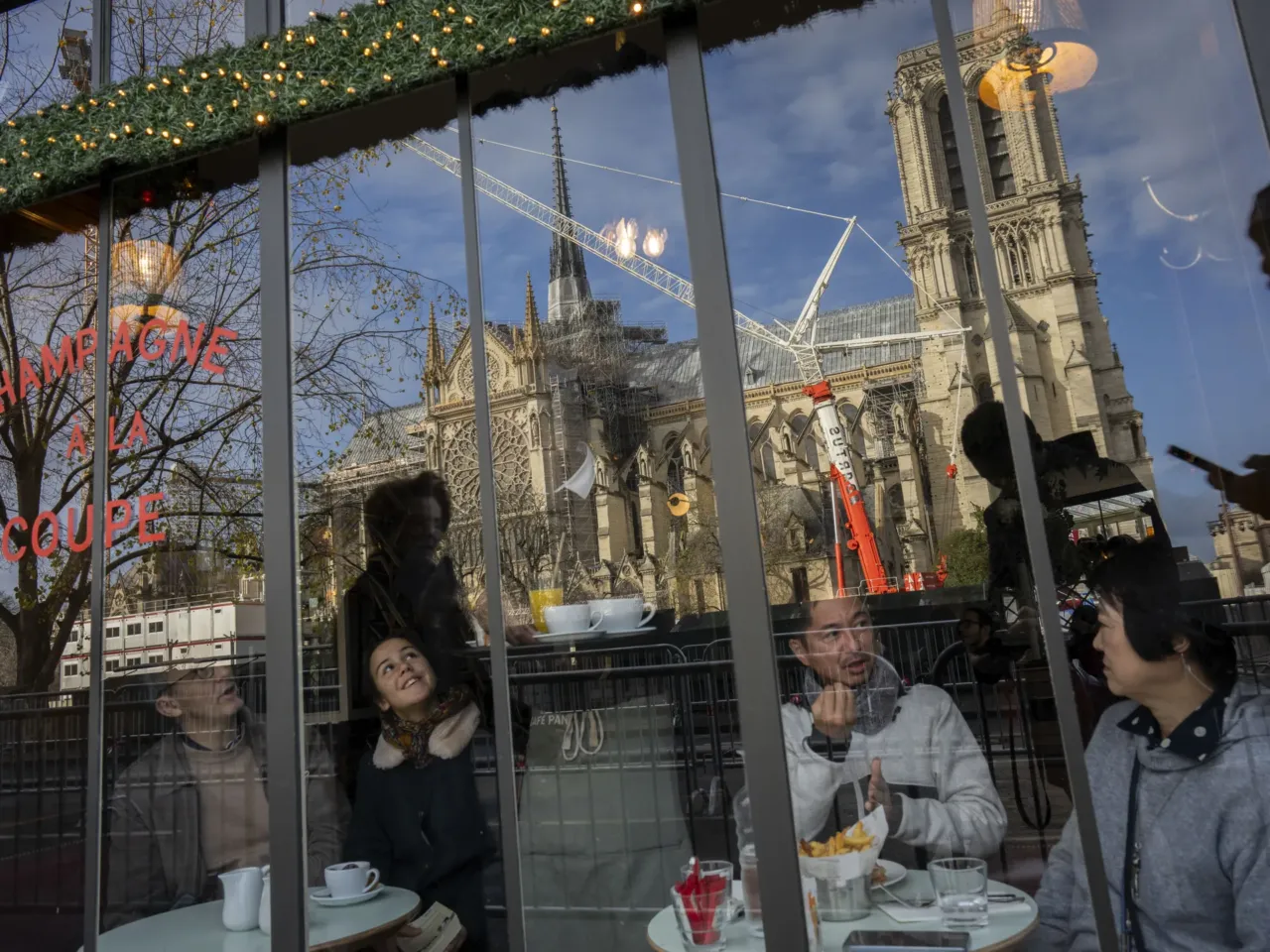 Customers sit inside a restaurant next to France's iconic Notre Dame Cathedral, hours before formally reopening its doors on Saturday.