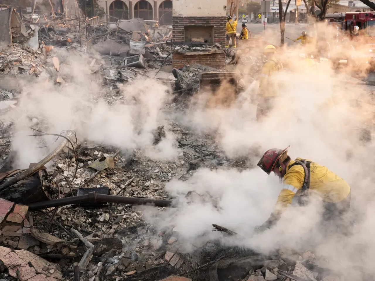 Friday, Jan. 10: A firefighter clears away smoking debris at the site of a structure on Lake Avenue in Altadena.