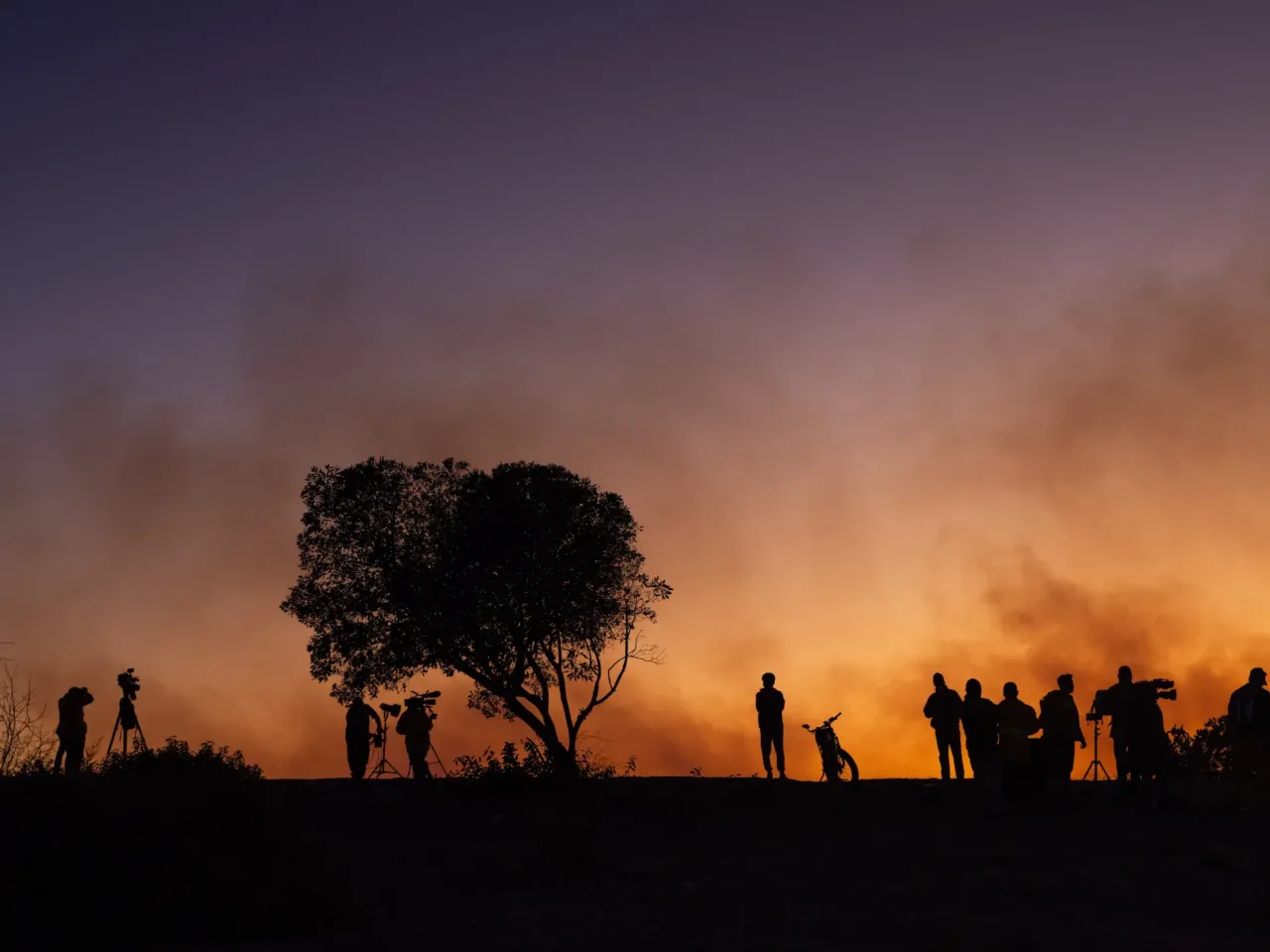 Saturday, Jan. 11: Media and civilians line a hillside in the Mountaingate development, above Mandeville Canyon, after the sun went down and fire air operations continue to work to extinguish flames from the Palisades Fire.