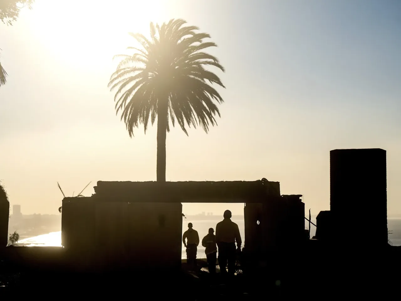 On Sunday, firefighters from an Oregon strike team survey damage at a Sunset Boulevard home leveled by the Palisades Fire in the Pacific Palisades community.