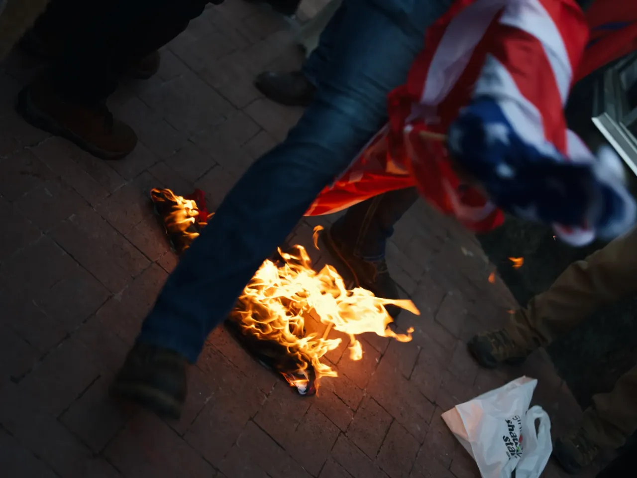 A group that is against President Trump burn a flag in protest outside of Capital One Arena.