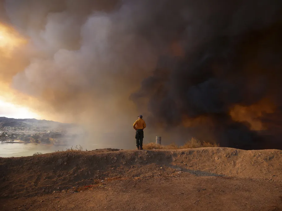Farmworkers feed the country, but who protects them from wildfire smoke? 2 A firefighter looking out towards Lake Castaic stands on a mound backdropped by clouds of smoke caused by the Hughes Fire in Castaic, Calif., Wednesday, Jan. 22, 2025.