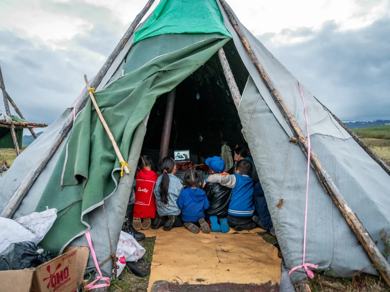Children gather inside a traditional tent, known as an ortz, in the Siberian taiga of northern Mongolia, watching a documentary about a Norwegian reindeer herder who was visiting to learn about the lifestyle of the region's nomadic Dukha reindeer herders. Despite the community's remote location deep in the forest — accessible only by horseback or reindeer — families stay connected with the outside world with solar panels, car batteries and the occasional wi-fi connection.
