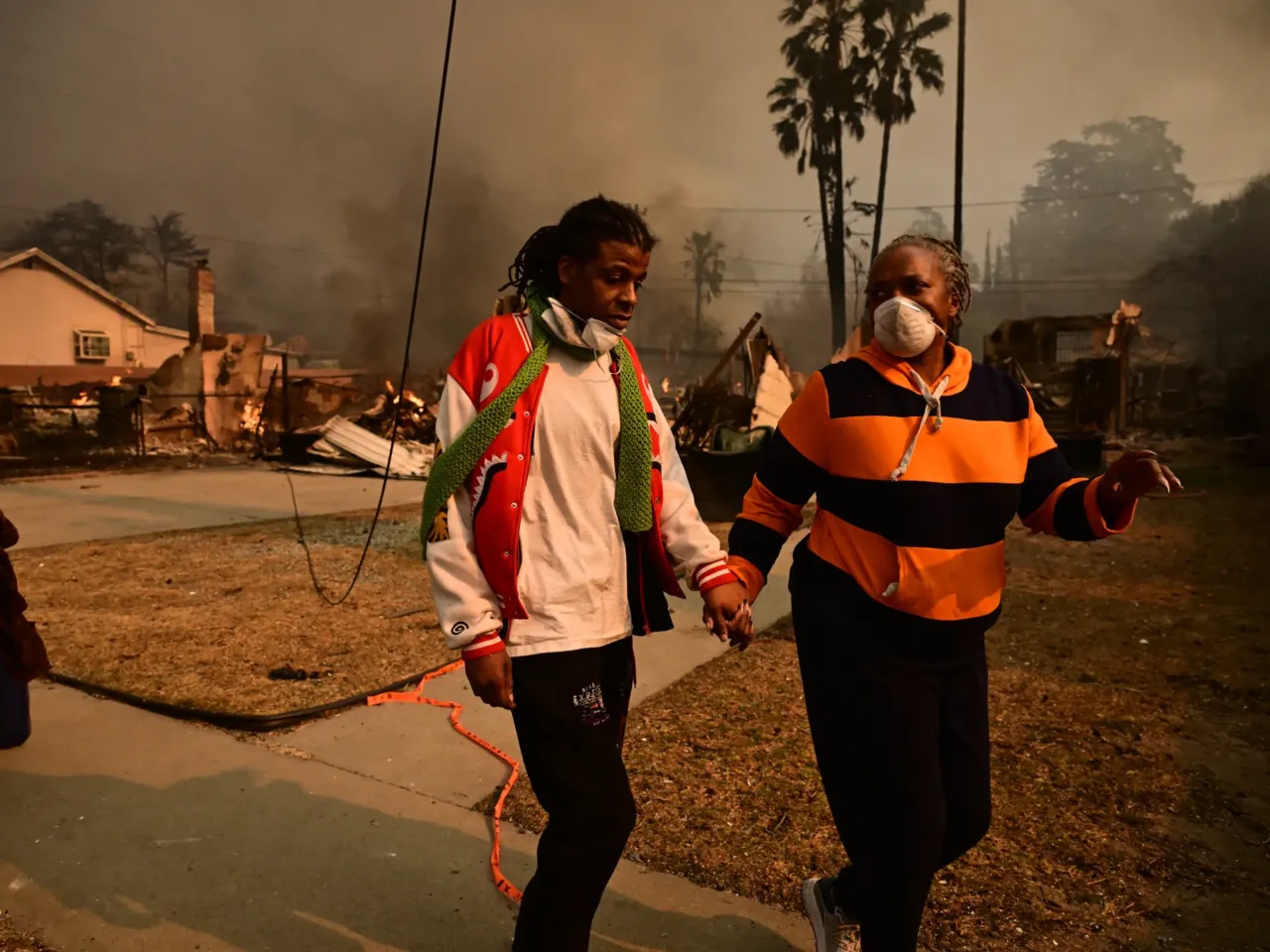 Power lines sparked new fires in LA after the Eaton Fire began, radio traffic shows 1 Residents walk past homes burnt by the Eaton Fire in Altadena on Jan. 8.
