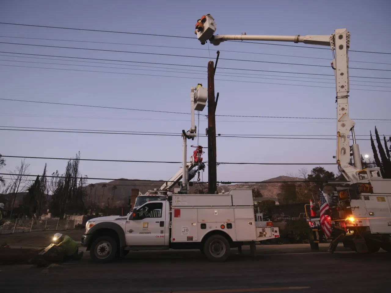 Power lines sparked new fires in LA after the Eaton Fire began, radio traffic shows 2 Southern California Edison workers service a utility pole in the aftermath of the Eaton Fire in Altadena on Jan. 12.