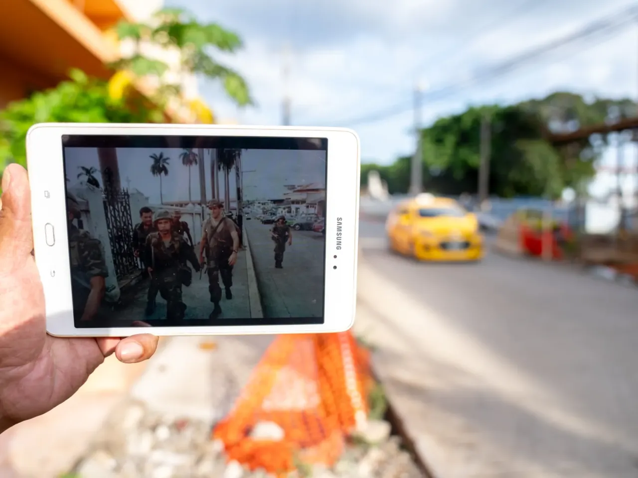 Efraín Guerrero holds a tablet showing a photograph of American soldiers walking up the same street in El Chorrillo neighborhood. American troops were searching for Manuel Noriega.