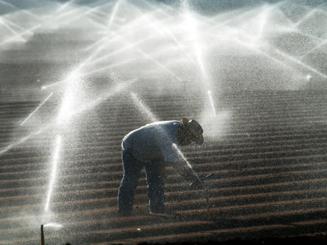 Trump funding freeze includes payments to keep the Colorado River flowing 2 A farm worker adjusts sprinkler heads spraying water that comes from the Colorado River Oct. 18, 2002 near El Centro, Calif.