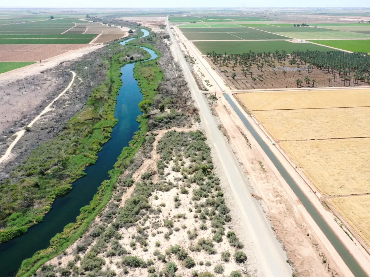 An aerial view shows the long-depleted Colorado River (L) as it flows between California (R) and Arizona, and an irrigation ditch (R) carrying river water toward Quechan tribal land on May 26, 2023 near Winterhaven, Calif.