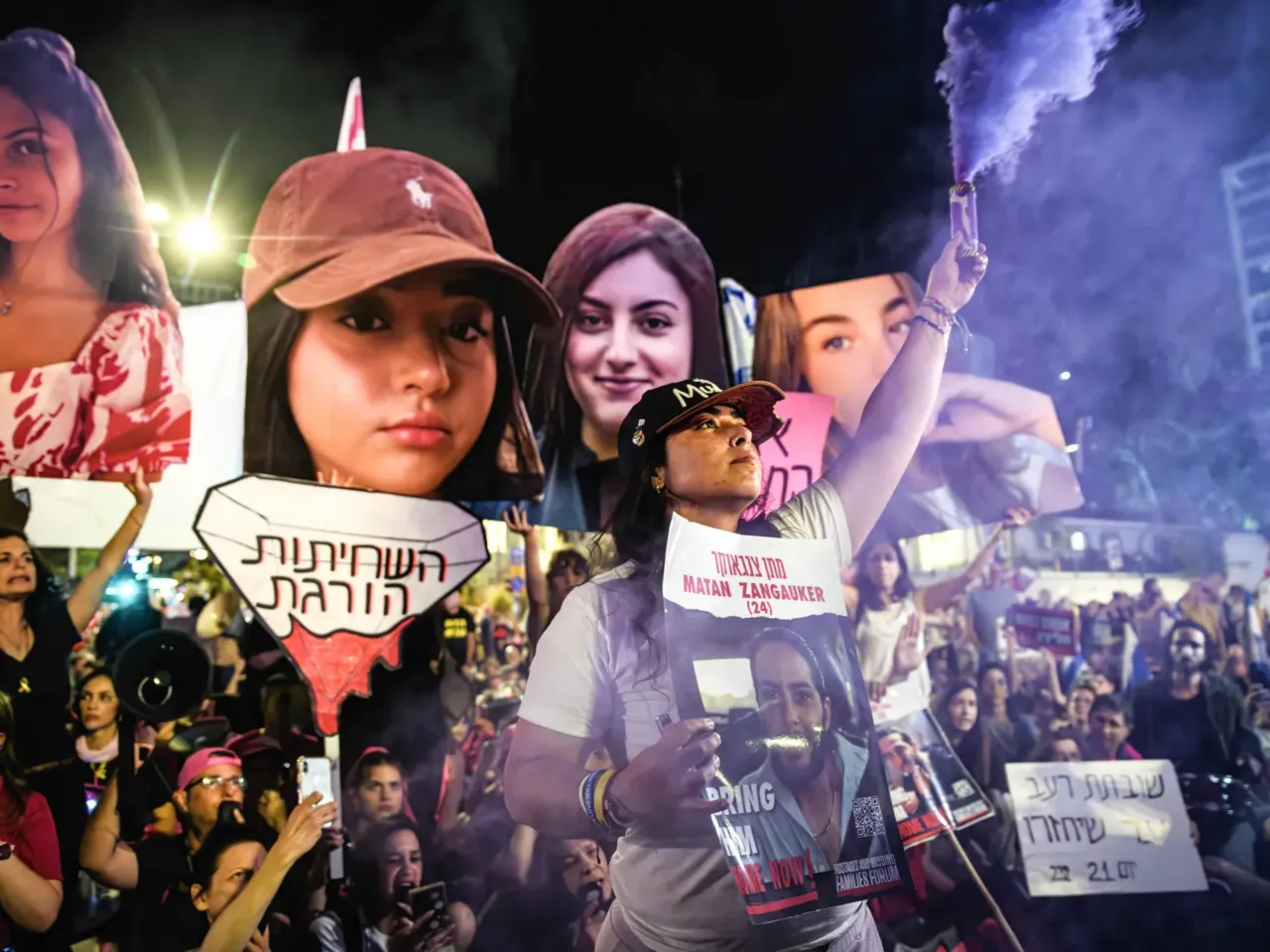 Released hostage Ilana Gritzewsky holds a photo of her boyfriend, Israeli hostage Matan Zangauker, still held in Gaza. In her other hand, she holds a flare next to photos of other hostages, May 25, 2024.