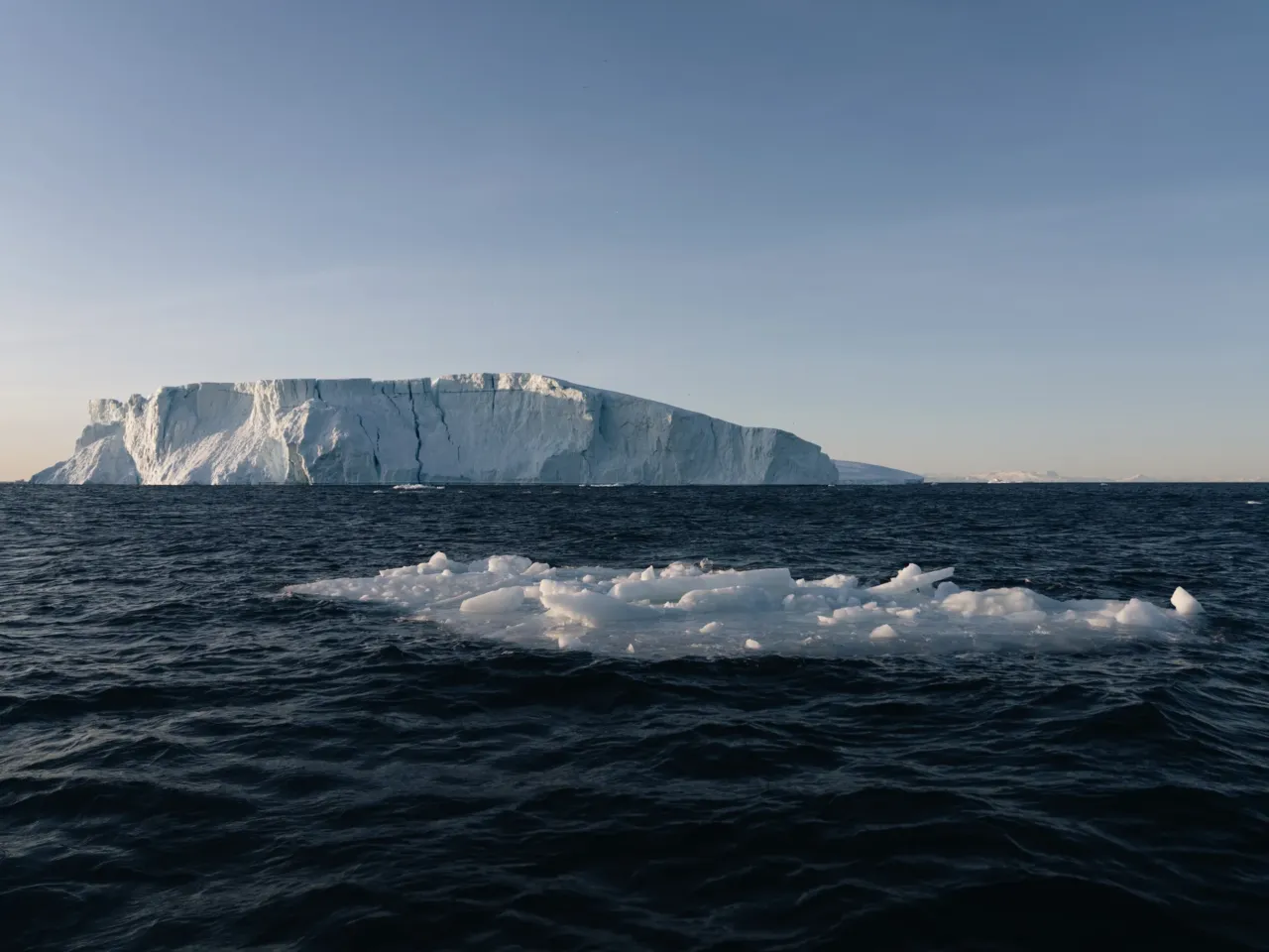 A piece of ice broken off from an iceberg floats in the ocean.