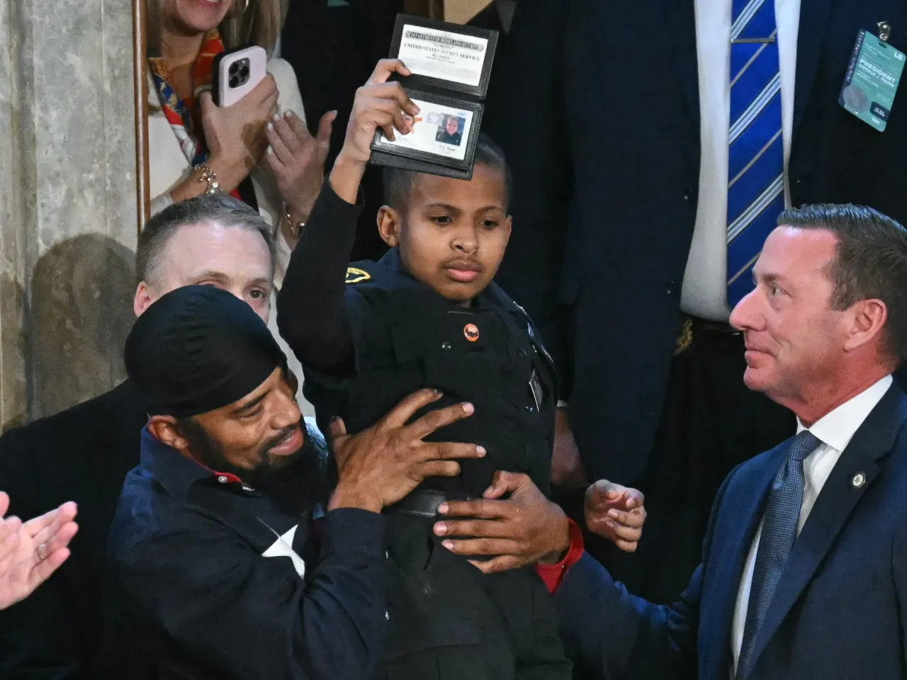 From cheers to protests, here's a look inside the chamber during Trump's speech 8 13-year-old cancer survivor Devarjaye "DJ" Daniel is lifted up by his father Theodis Daniel after President Trump made him an honorary member of the US Secret Service during his address to a joint session of Congress.
