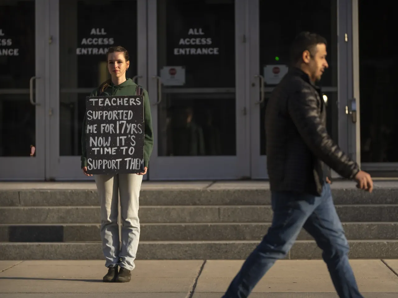Chloe Kienzle of Arlington, Va., holds a sign as she stands outside the U.S. Department of Education, in Washington, D.C., on Wednesday – the day after the Trump administration announced widespread job cuts at the agency.