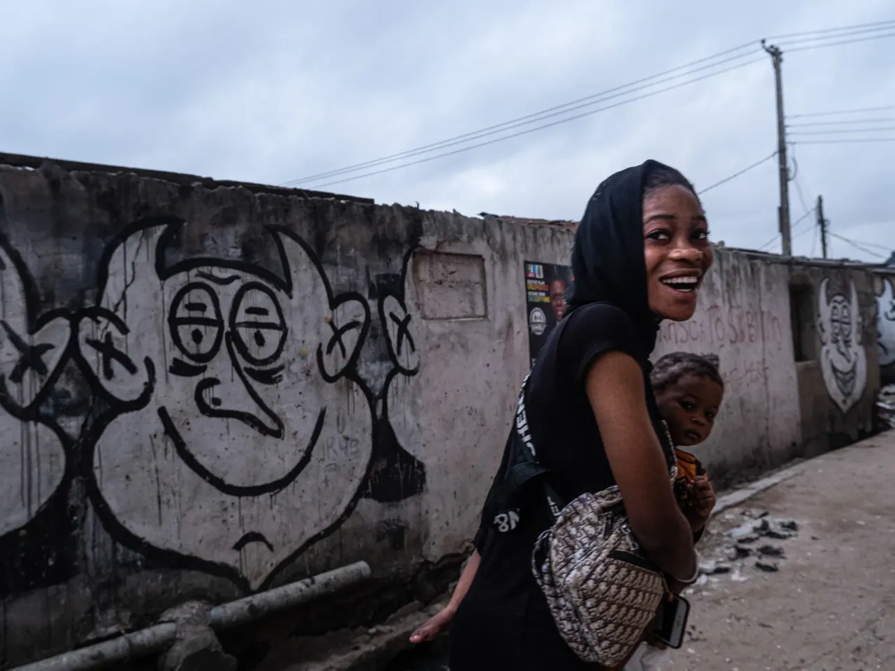 A woman takes a young girl to school in Bariga, Lagos. Photographer Fawaz Oyedeji says: "I had just started shooting that calm morning for a project on election posters when she passed by carrying a girl and a schoolbag. Her unexpected smile set a friendly pace for the rest of my day in the field."