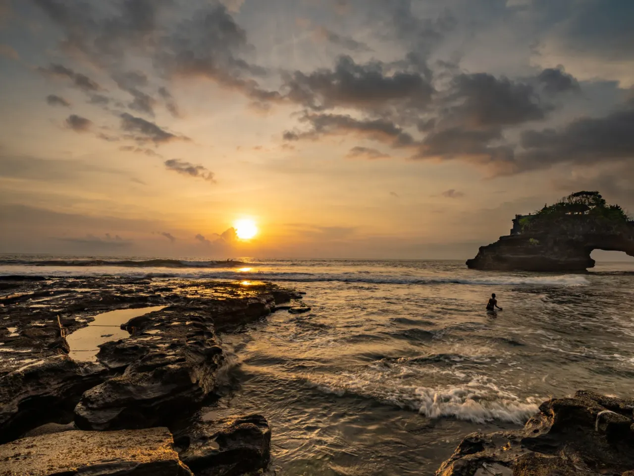 A child plays in the sea near the Pura Batu Bolong Hindu temple at Bali, Indonesia, located on the natural arch bridge. Photographer Amrita Chandradas was "in awe" of the intricate rock formations '' and says the sight of the child "frolicking among the waves" created "a moment of pure tranquility."