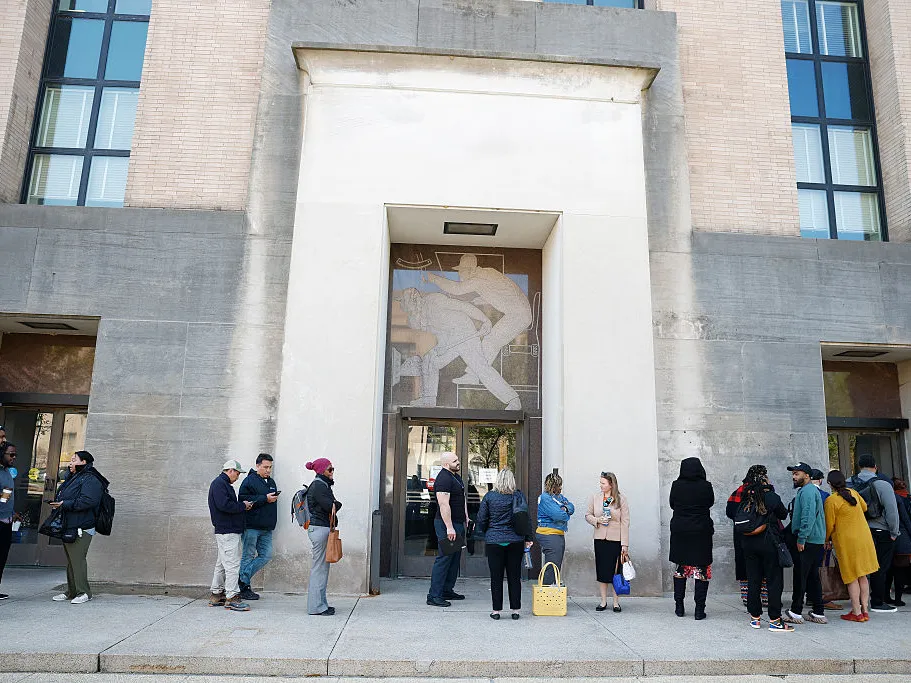 Employees of the Department of Health and Human Services stand in line to enter the Mary E. Switzer Memorial Building on April 01, 2025 in Washington, DC. Widespread layoffs began Tuesday across the agency.