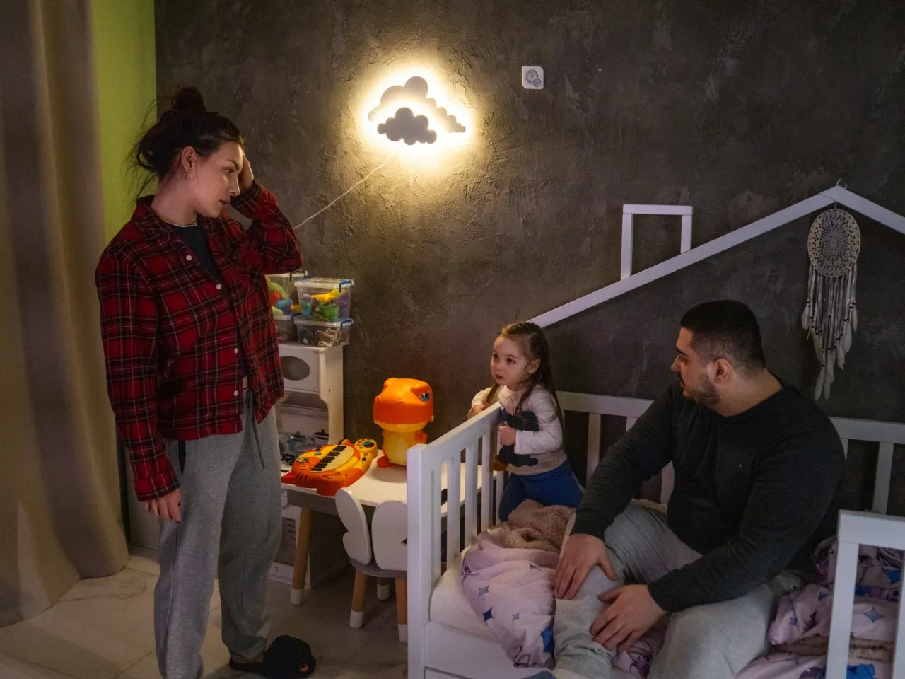 Hanna and Arkadii Rubin try to convince their daughter Leya, 2, to go to bed, although she doesn't want to. They live in an apartment in Kharkiv where, just over a year ago, part of the building was damaged in a missile attack.