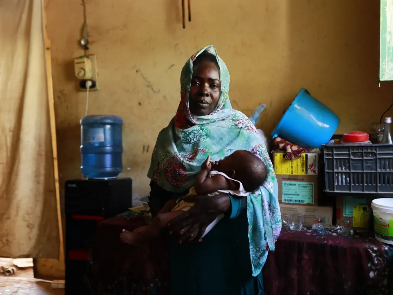 Maryam holds the 7-month-old child she gave birth to inside a refugee camp in Gezira, Sudan, on Dec. 10, 2023. "I traveled from Mayo, in southern Khartoum, to the city of Wad Madani," she says. "The trip took three days on a karoo [a wooden cart pulled by a donkey], and I was with my six children and was five months pregnant at the time."