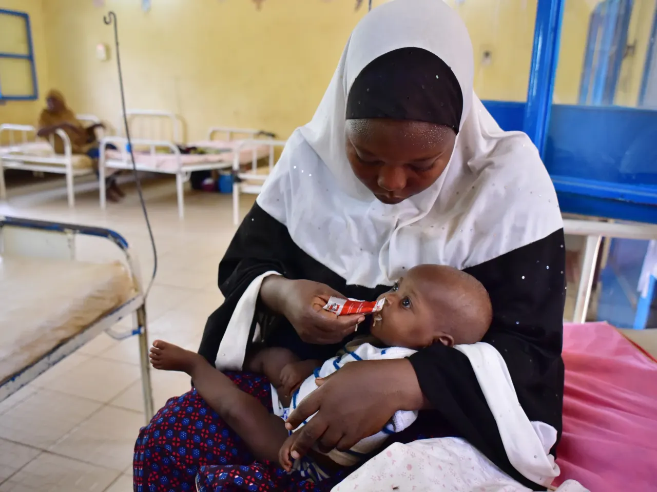 Where's Plumpy'Nut? A lifesaving food for malnourished kids is caught up in U.S. cuts 1 This photo taken on June 14, 2016 shows a woman feeding her child suffering from malnutririon with a pack of "Plumpy Nut" food, which contains vitamins, proteins and all neccesary nutriments, in the pediatrics unit at the Niamey hospital. Plumpy Nut is now manufactured locally, a few kilometers away in the industrial area of Niamey, by the Societe de Transformation Alimentaire (STA, or Food Transformation Company. Niger has been repeatedly plagued by food and humanitarian crises, as more than 300,000 people have been displaced. 240,000 have fled the atrocities of the Nigerian Islamist group Boko Haram in the southeast, while 60,000 have fled to Niger to escape the Islamist groups in Mali.