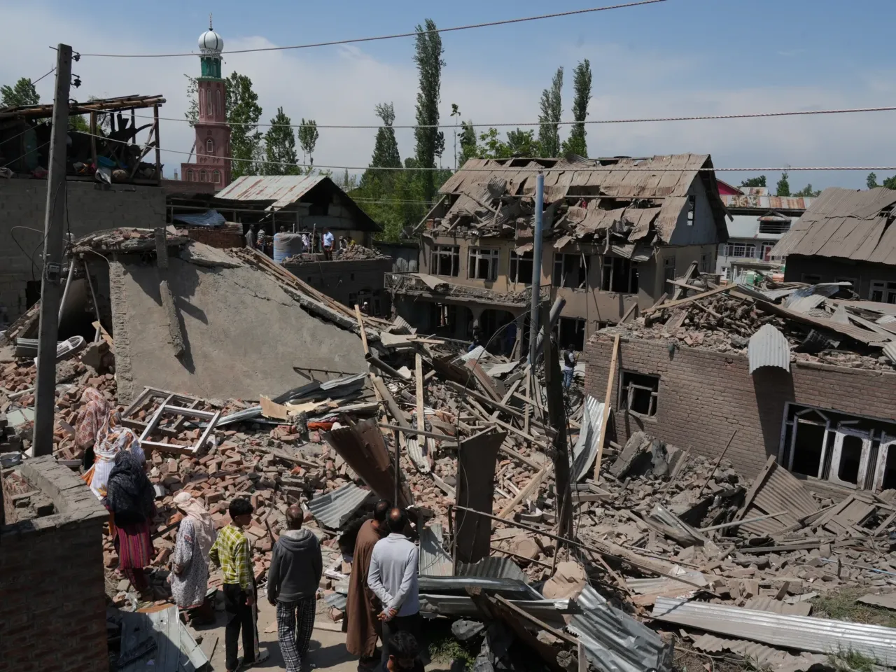 People stand near the razed house of Kashmiri militant Ahsan Ul Haq Sheikh's family house in Murran area of Pulwama district on April 26, 2025.
