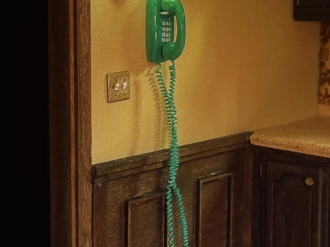 A tiny blue phone is shown in a vintage kitchen created by artist Marina Totino.