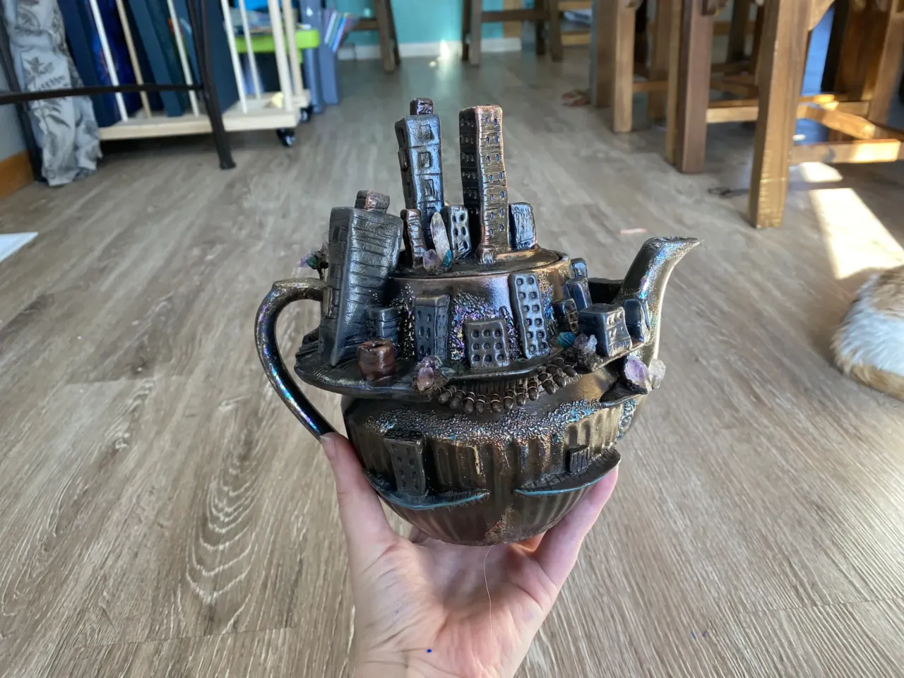 Ashley Voortman shows off a teapot she made with a tiny abandoned city on it.