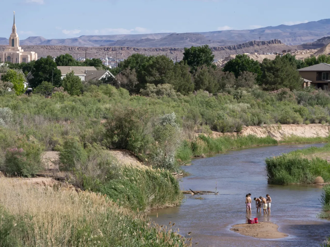 People wade in the shallow waters of the Virgin River in St. George, Utah. The river provides the desert community with water, but climate change and a growing population threaten that supply. Local leaders are looking toward recycled sewage as a solution.