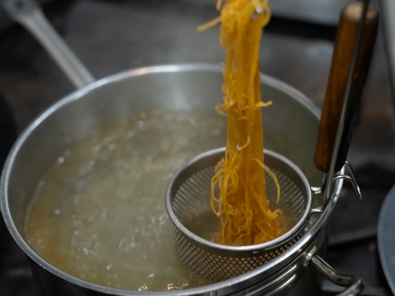 Chef Shuai Wang strains the wonton noodles for the crispy smoked duck dish. "You talk to a legit Chinese person, they'll know when the noodles are literally two, three seconds overcooked," he says.