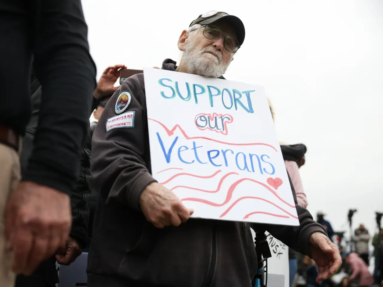 John Spitzberg, 87, holds a "Support our Veterans" sign during a "Veterans March" at the National Mall on March 14, 2025, in Washington, D.C. The 87-year-old veteran was arrested June 13 at the U.S. Capitol while protesting the U.S. Army's 250th anniversary parade which coincided with President Trump's 79th birthday.