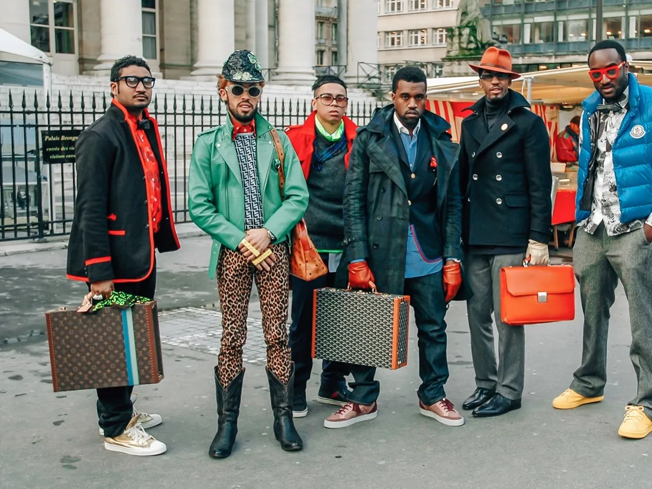 Virgil Abloh (far right) with his then-employer Kanye West (center, holding briefcase) at Paris Fashion Week in 2009.