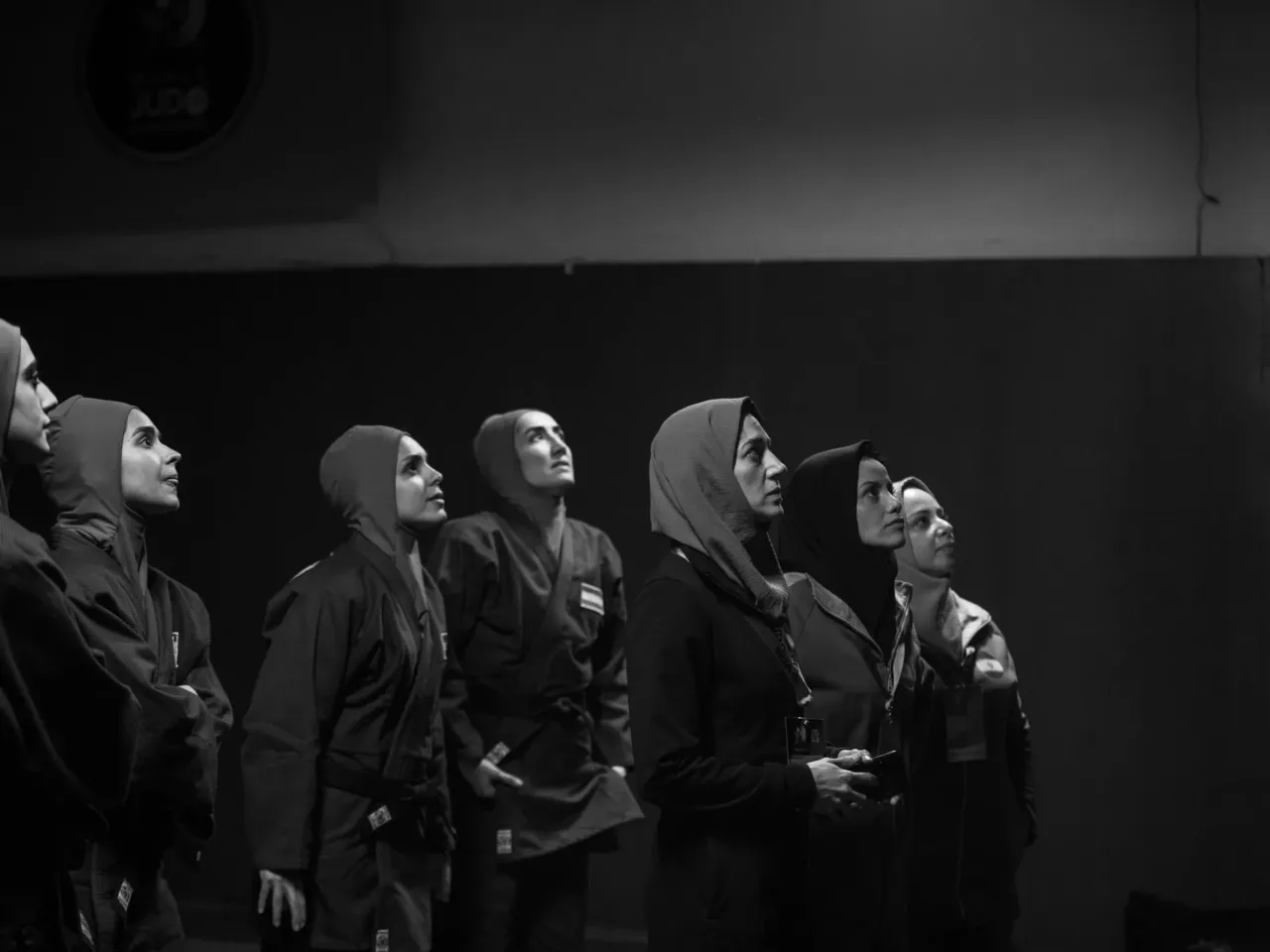 Coach Maryam Ghanbari, played by Tatami co-director Zar Amir (center), watches the screen with other judo athletes as Leila's match begins.