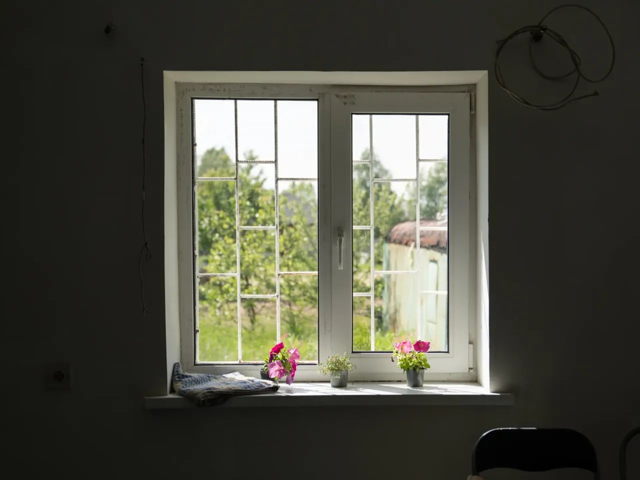 Millions of Ukrainians abroad hope to return home once Russia's invasion ends 2 Flowers sit on a windowsill in the house in Horenychi. The home is surrounded by trees. The noise from drones, missiles and air defense in Kyiv aren't as loud here.