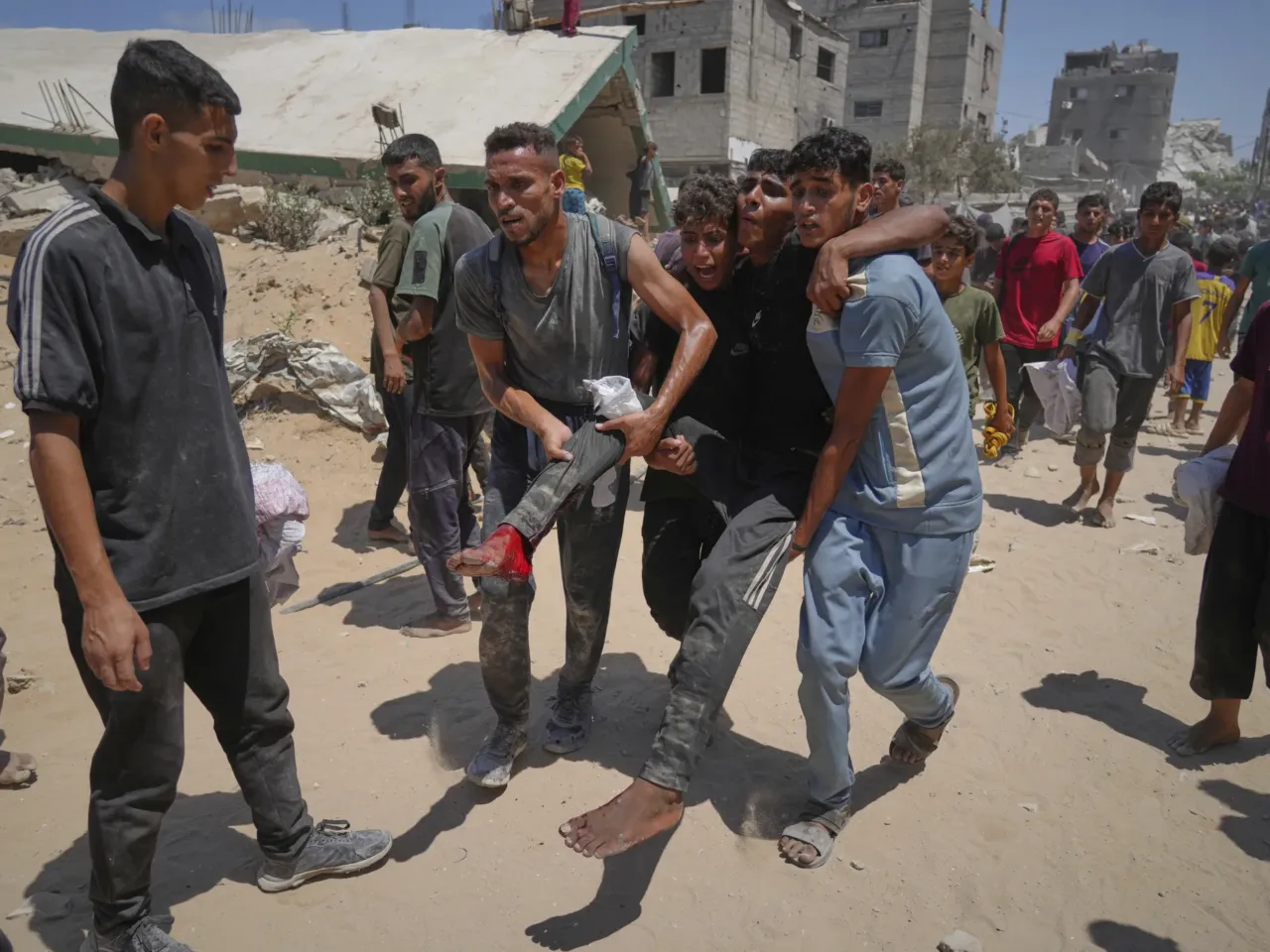 Palestinians carry a wounded man who was injured while rushing to collect humanitarian aid airdropped by parachute into Gaza City, in the northern Gaza Strip, on Aug. 7.