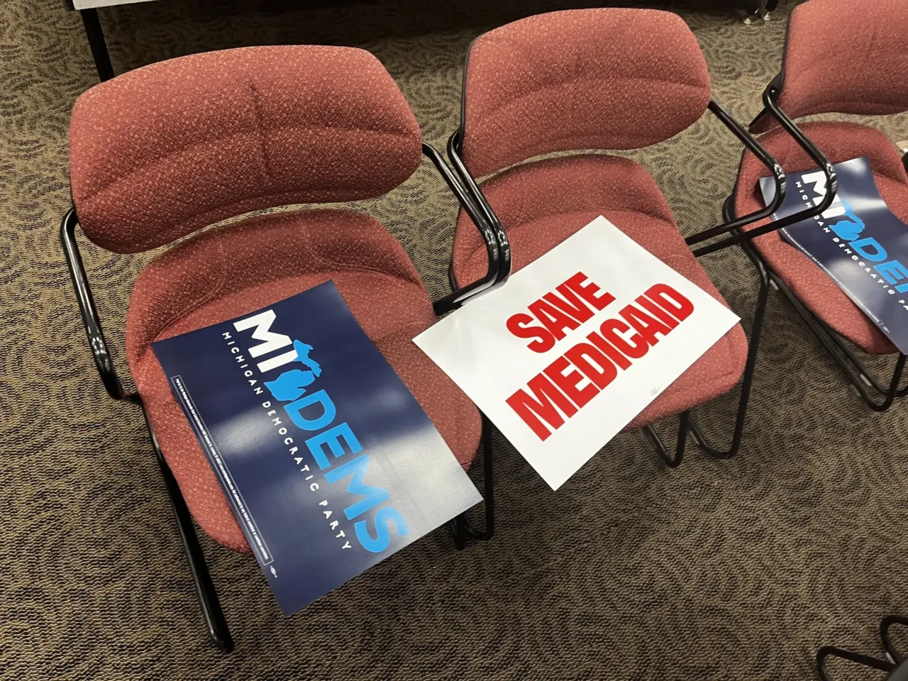 Two campaign signs sit on chairs at a Democratic town hall event in Macomb County, Michigan.