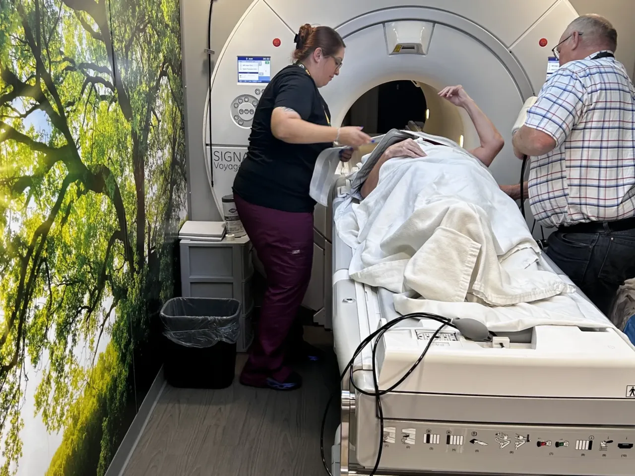 MRI technician Helen Cryan gets Retta Jacobi ready for her scan inside a mobile imaging semitrailer at Southwest Healthcare Services in Bowman, North Dakota, with the help of the truck's driver, Kevin Kraft, who also works as a medical assistant.