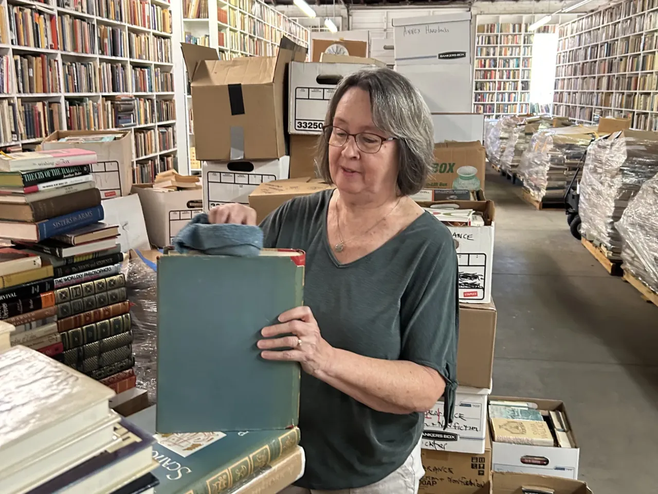 Peggy Terrell volunteers cleaning books at the Larry McMurtry Literary Center and bookstore in Archer City, where some of the collection is still stored in pallets.